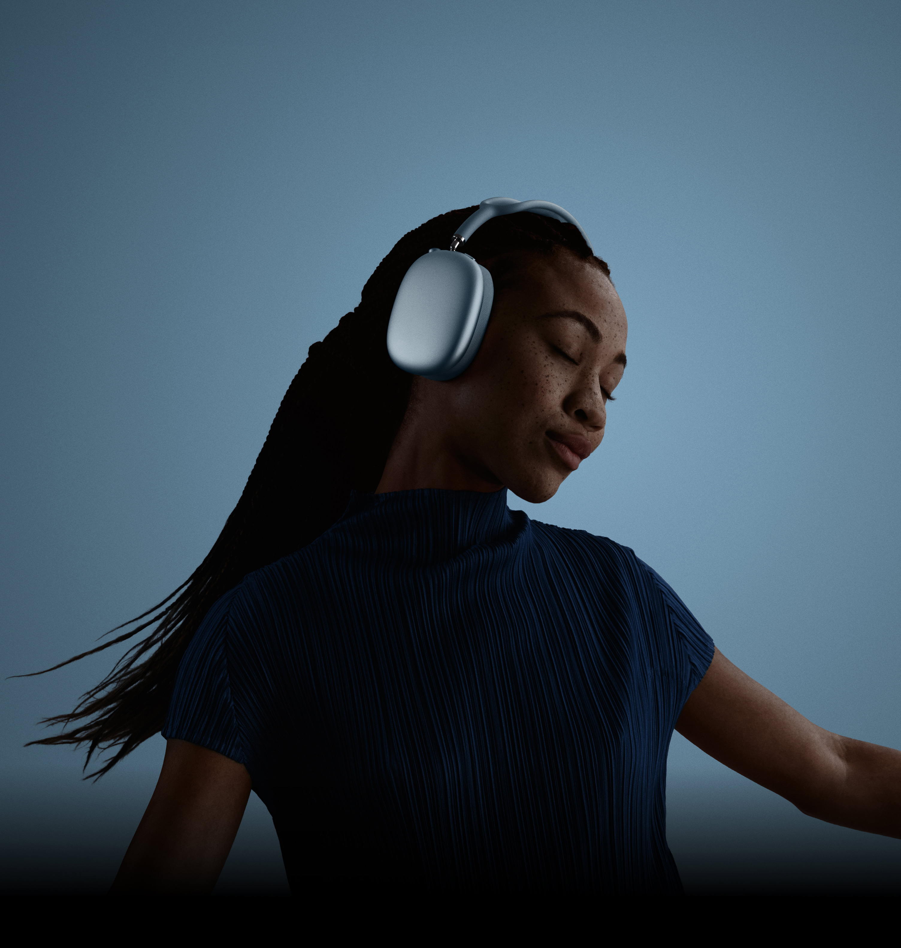 Une femme avec les yeux fermés, la tête penchée vers la gauche, portant des AirPods Max.