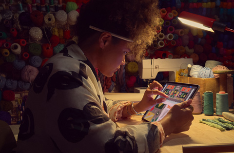 Uma pessoa sentada à secretária usa dois dedos no ecrã de um iPad para ampliar uma imagem.