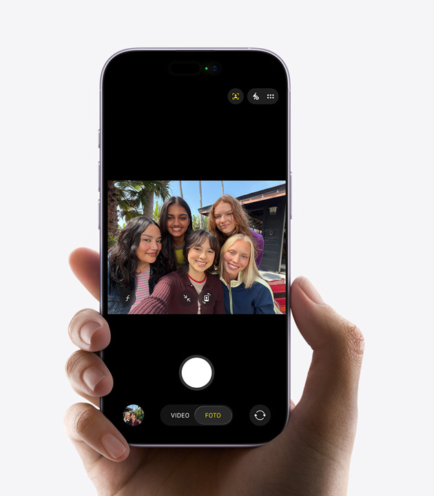 iPhone mostrato di fronte, tre persone inquadrate dalla fotocamera frontale Center Stage per un video selfie, con quadrati gialli attorno ai volti a indicare l’inquadratura automatica