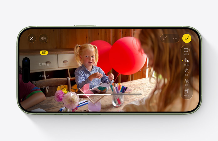 풍선이 있는 테이블에서 놀고 있는 아이의 동영상을 촬영하면서 오디오 믹스 기능을 사용하는 모습을 보여주는 iPhone 17 앞면