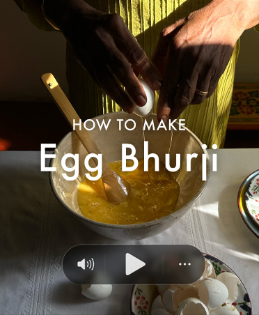 Still from cooking video, man breaking eggs into bowl